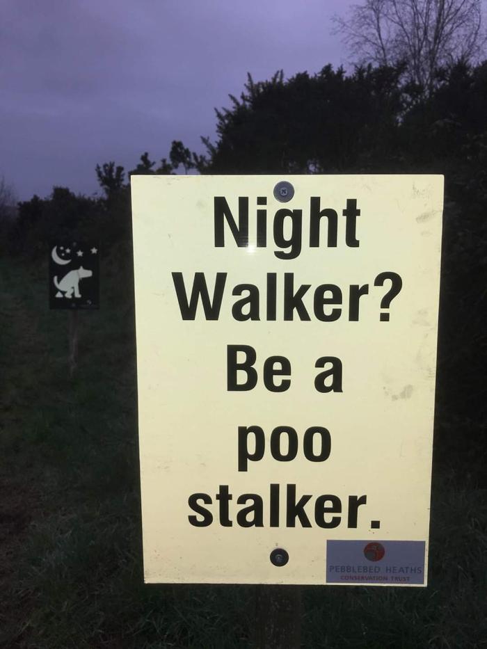 Glow in the dark sign about picking up poo